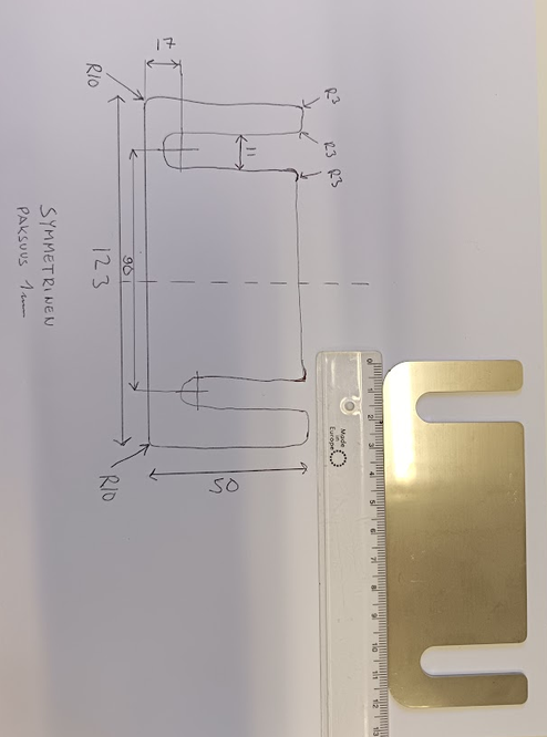 Laser-cut shim plate next to the original paper sketch and a ruler